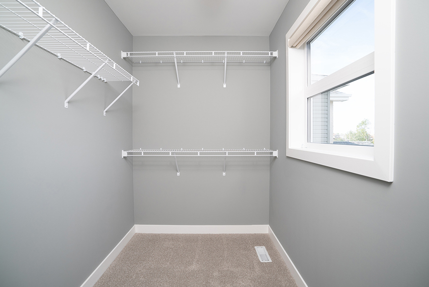 Walk-in closet with grey painted walls, wire shelving and picture window the preston broadview homes winnipeg