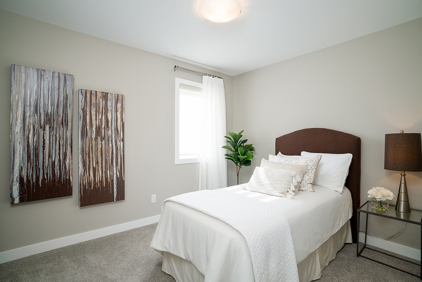 secondary bedroom with beige walls, beige carpet, white baseboards, white casing the preston broadview homes winnipeg
