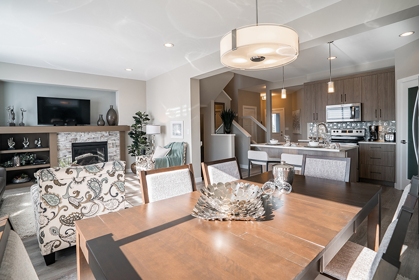 main living areas with kitchen, eating area and great room with beige walls and blue accents the preston broadview homes winnipeg