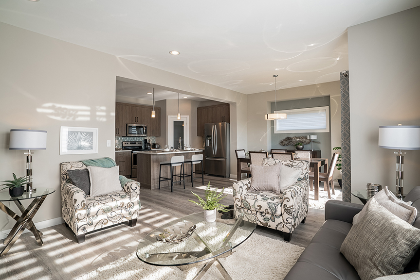 main living area with beige walls, view of the kitchen and vinyl plank flooring the preston broadview homes winnipeg